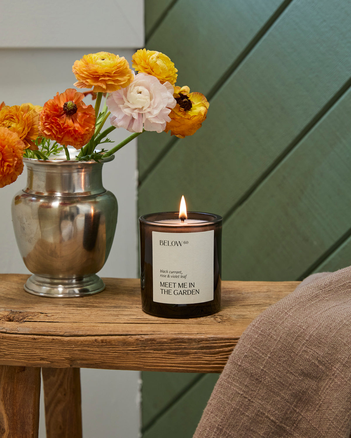 Candle with a decorative vase of flowers on a wooden surface