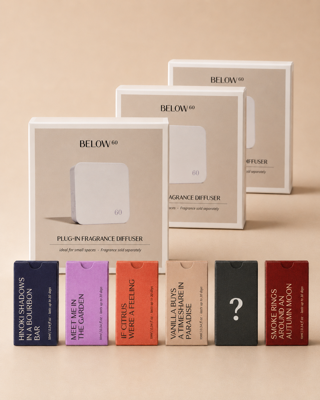 Three BELOW 60 plug-in fragrance diffuser boxes are arranged on a warm beige background, with six diffuser scent refill boxes in front. The diffuser packaging is white and beige, and the refill boxes are in dark blue, lavender, orange, black, and dark red, each printed with a scent name and one with a question mark.