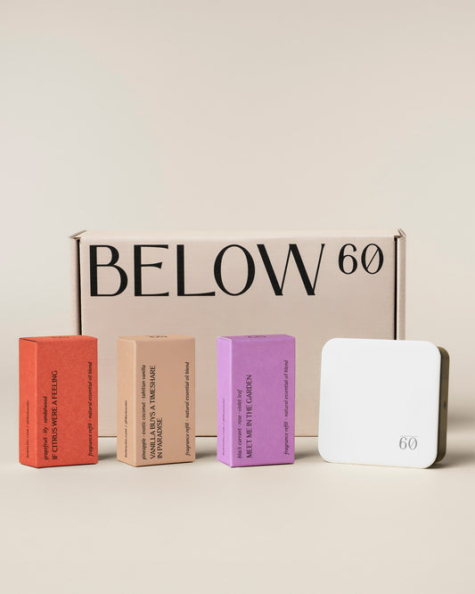 Below 60 Best Sellers Starter Kit on a clean neutral background. Three refill boxes are displayed left to right — If Citrus Were a Feeling in terra cotta, Vanilla Buys a Timeshare in Paradise in warm tan, and Meet Me in the Garden in soft lavender — alongside the white plug-in diffuser, with the Below 60 branded box behind them.