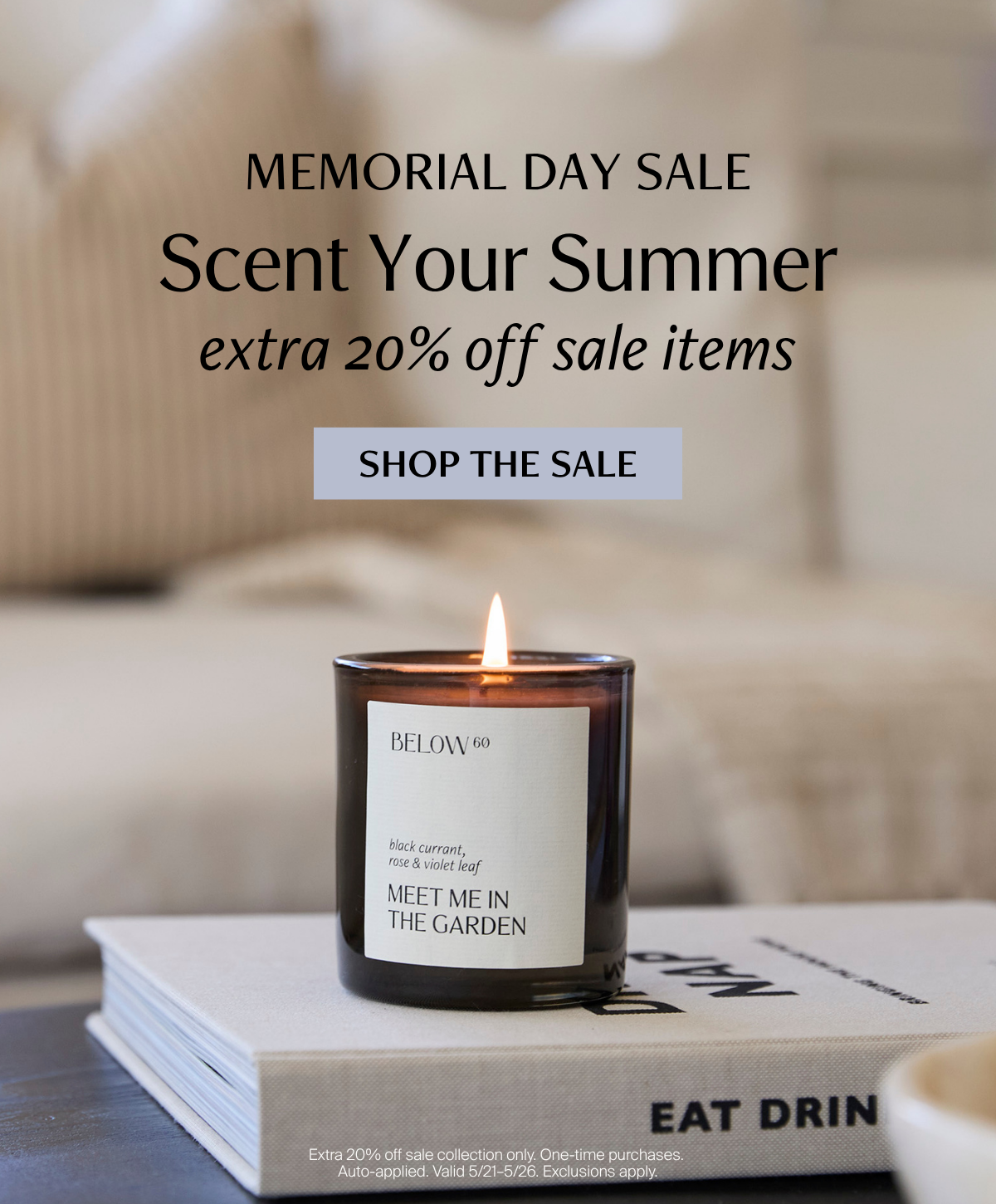 A lit Meet Me in the Garden candle by Below 60 resting on a stack of coffee table books against a soft neutral linen background. Text reads: Memorial Day Sale — Scent Your Summer, extra 20% off sale items.